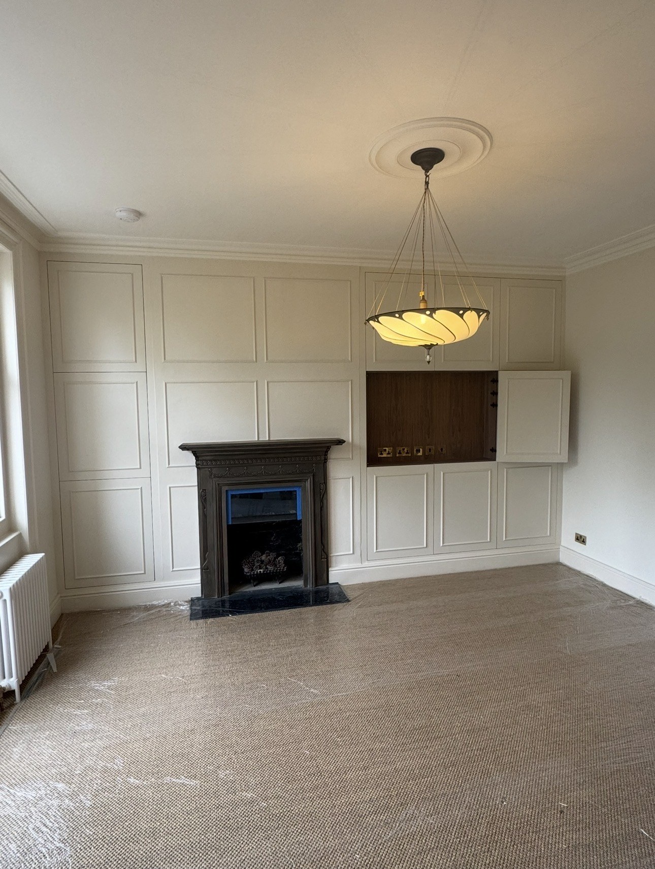 Media wall with the walnut veneer TV cabinet opened and the panelled doors closed around it