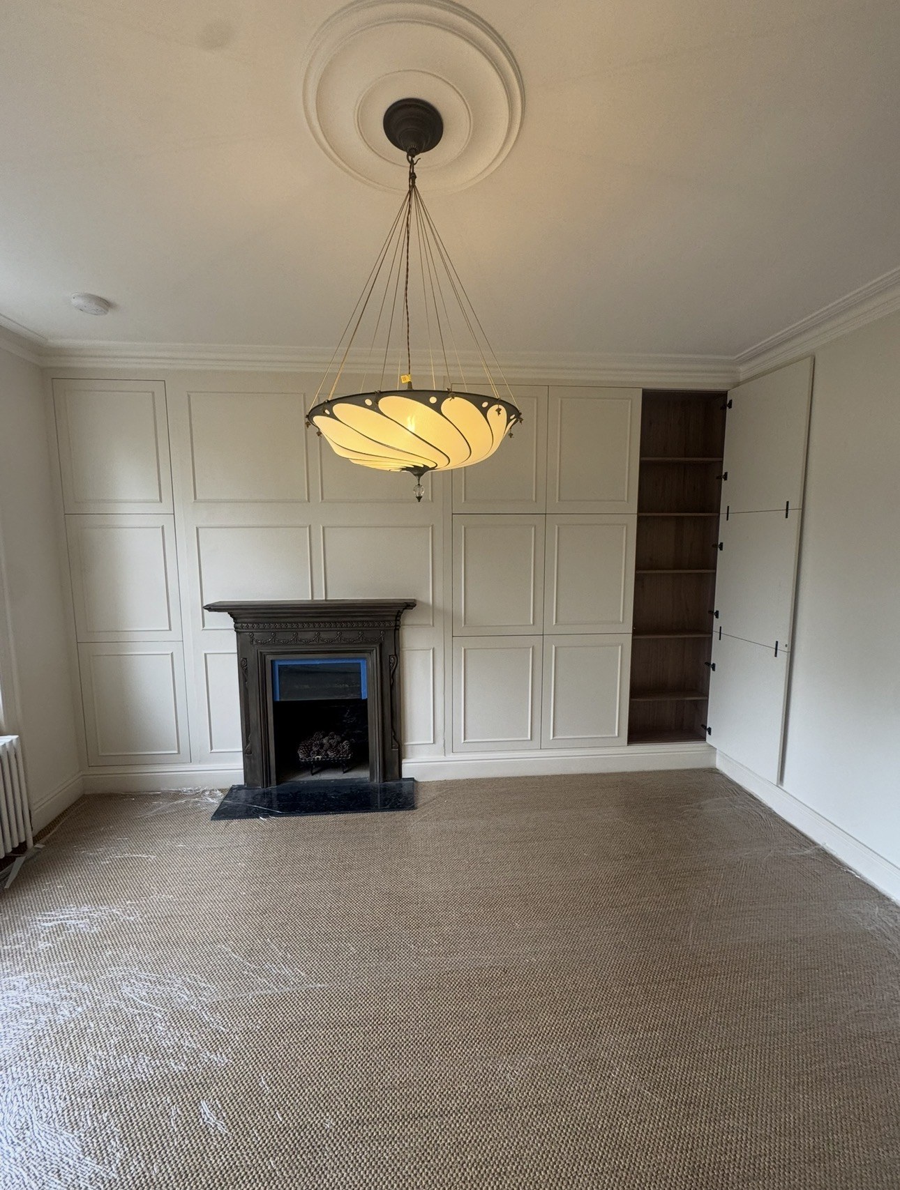 Open side storage showing walnut veneer shelving beside the fireplace