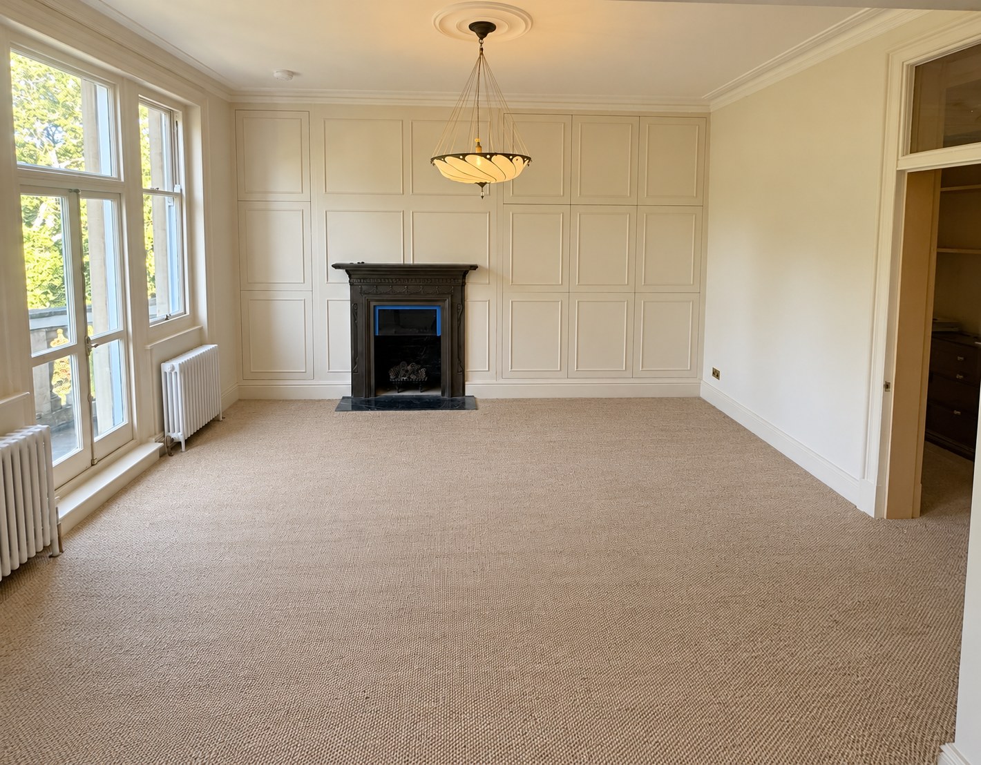 Victorian-style panelled media wall beside the original fireplace at York Mansion, Battersea