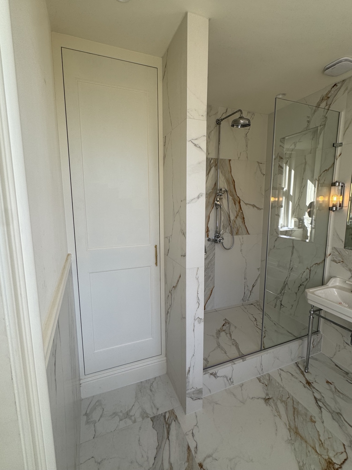 Tall fitted towel storage unit with a painted panelled door in the York Mansion master en suite