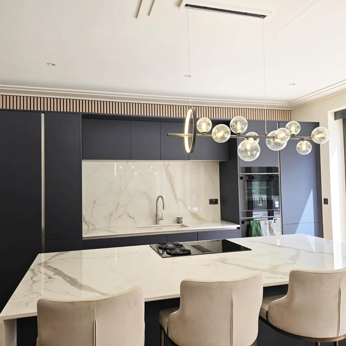 Closer view of the island, sink wall, cabinetry and pendant light