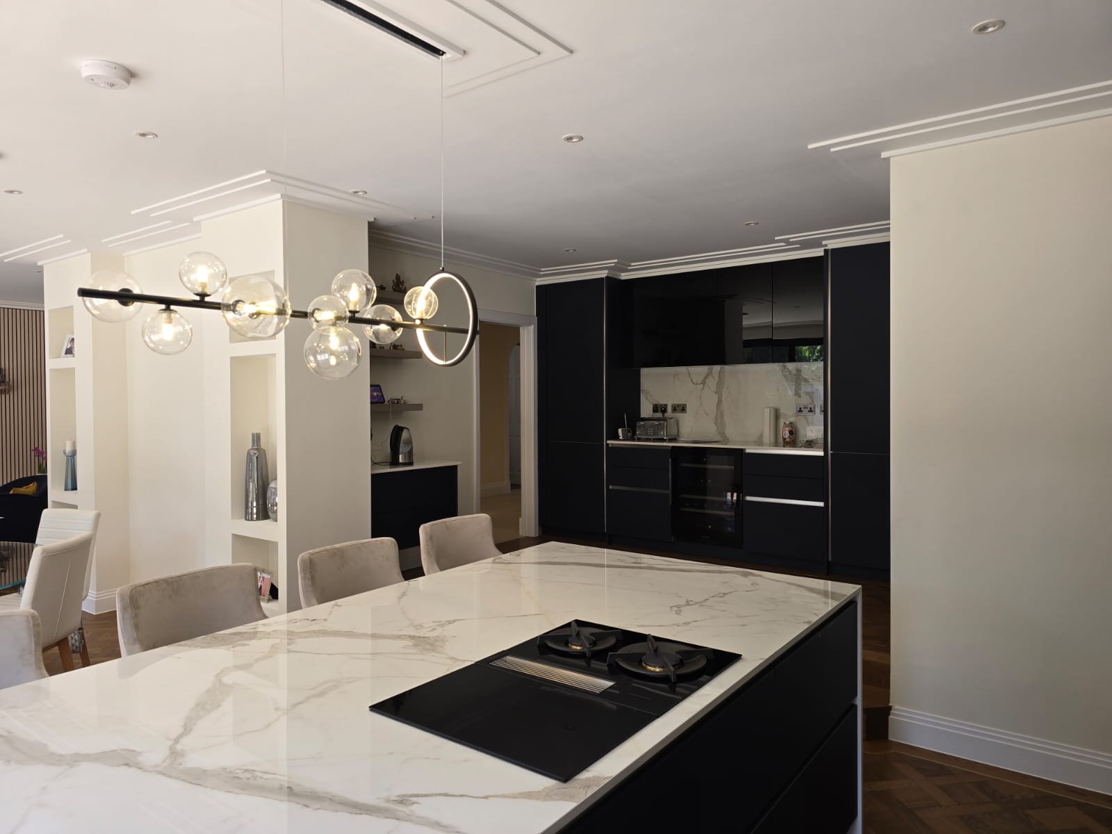 Dukes Wood Drive kitchen island with marble worktop, integrated hob and graphite cabinetry beyond