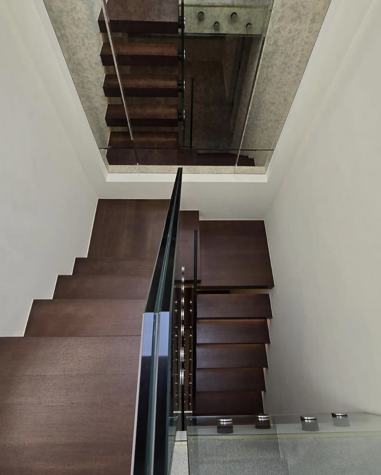 Upper landing view showing glass panels and the turn of the floating staircase