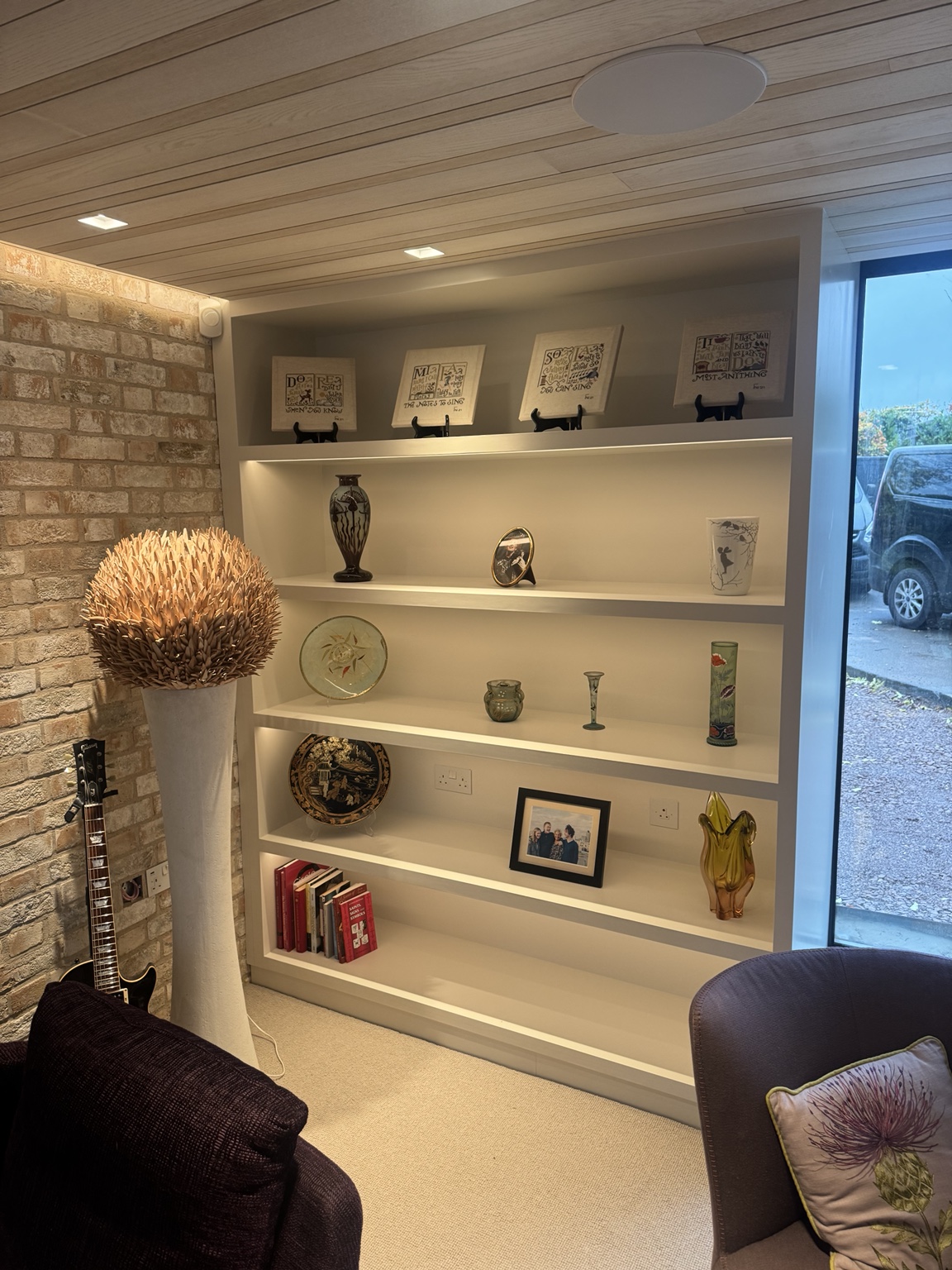 Closer view of illuminated open shelves beside the brick wall