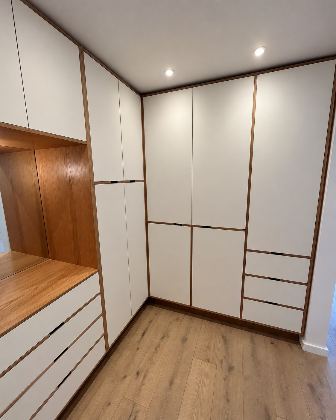 Full-height sprayed MDF cabinets and integrated handles in the master walk-in