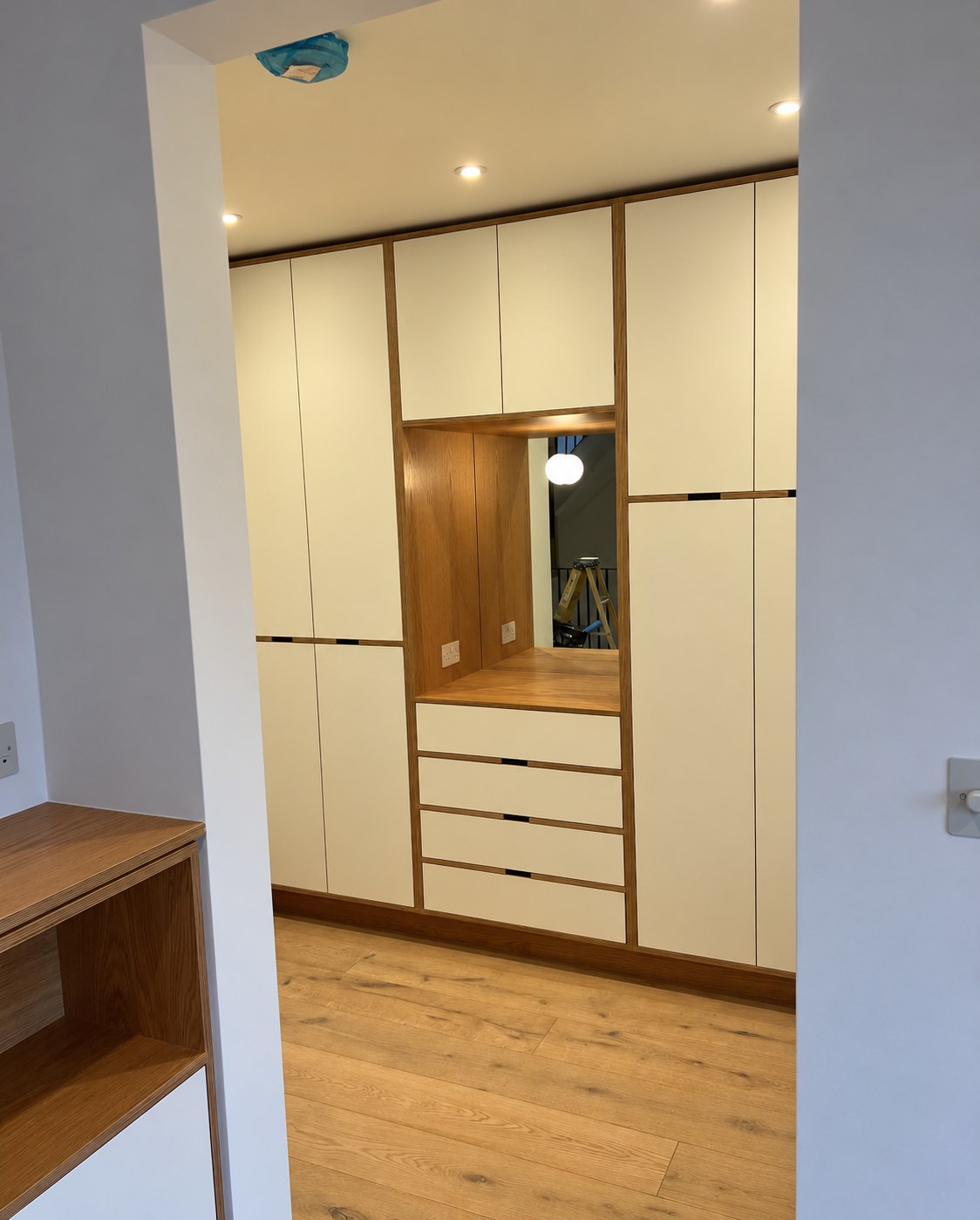 Walk-in wardrobe seen from the doorway with birch ply and sprayed MDF cabinets