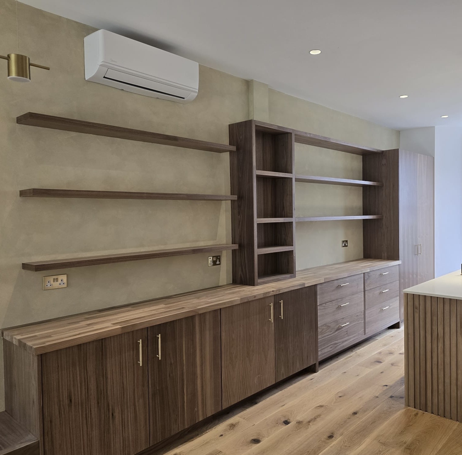 Clear-lacquered walnut veneer cabinetry, floating shelves and brass handles