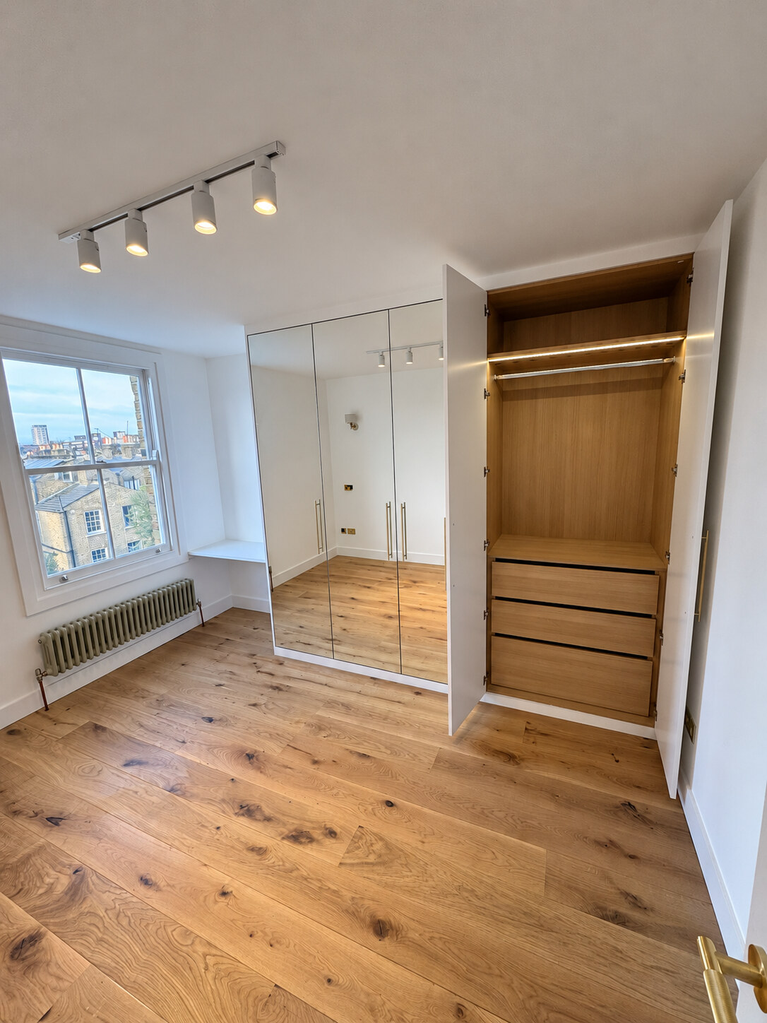 Bedroom three mirrored wardrobes with an open Sorano oak interior and desk by the window