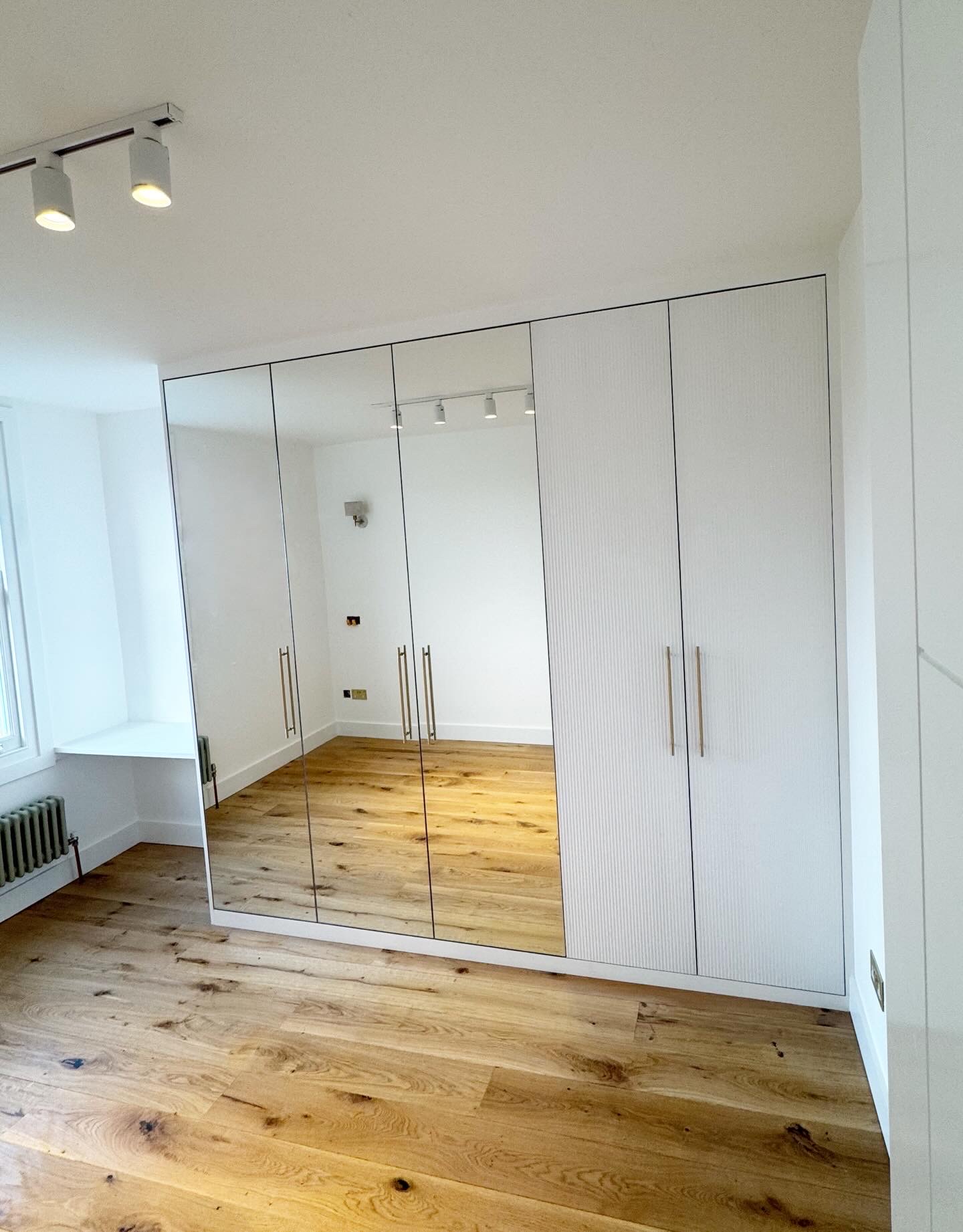 Bedroom three wardrobe with three mirrored doors, two ribbed doors and brass handles beside the fitted desk