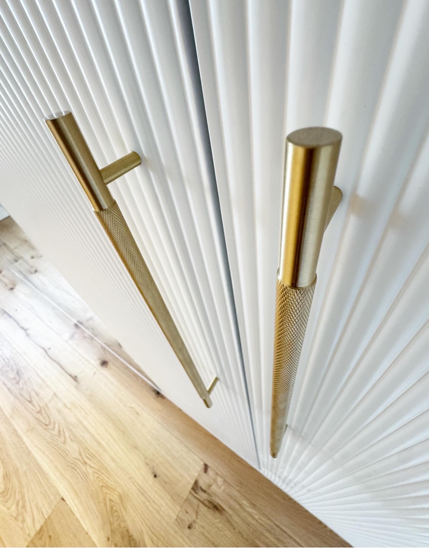 Close-up of brass handles on sprayed ribbed wardrobe doors