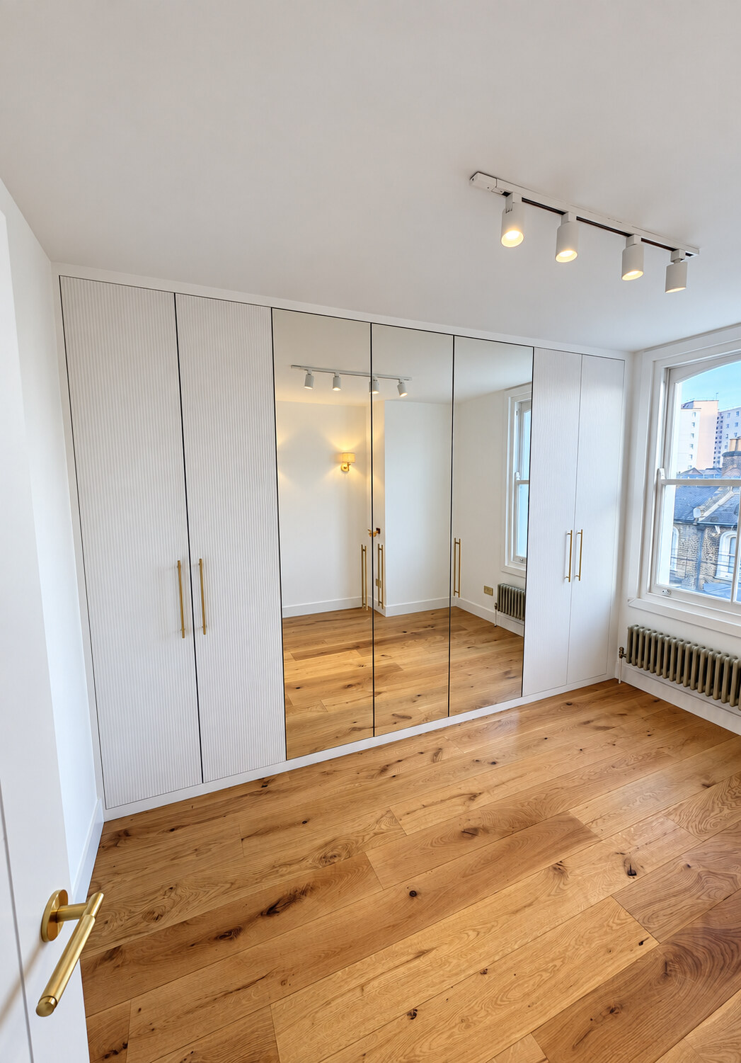 Sprayed ribbed wardrobe doors with mirrored fronts and brass handles at Cole Park Road