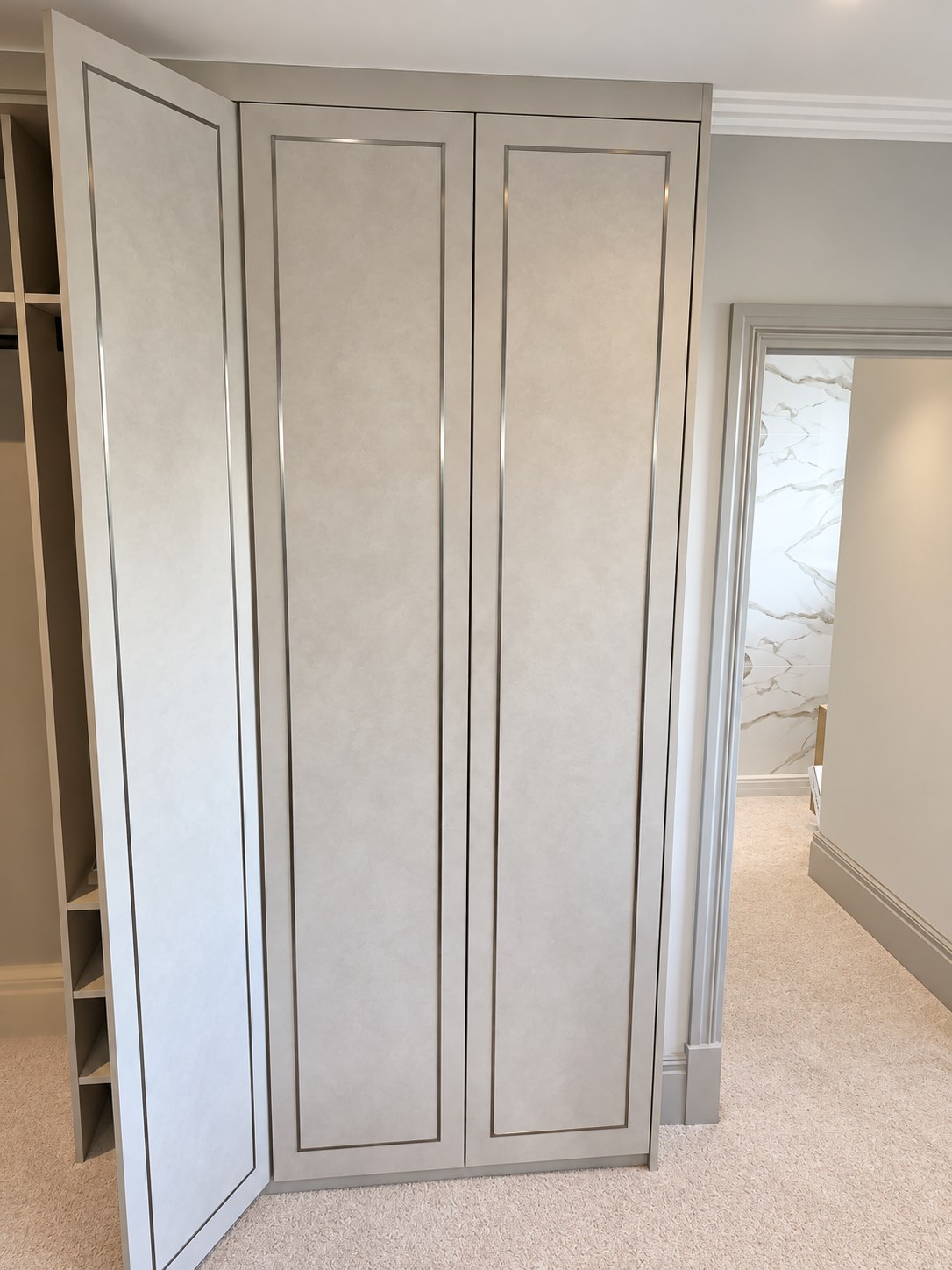 Three-door fitted wardrobe beside the en suite with one door open