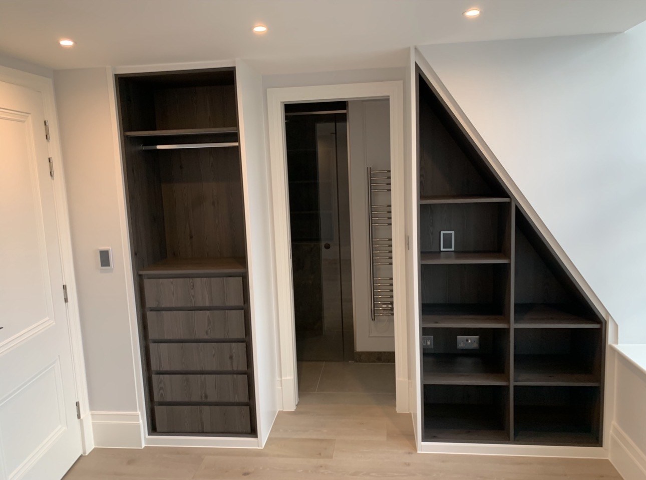 Dark oak fitted drawers and sloped open shelving in a Westminster apartment