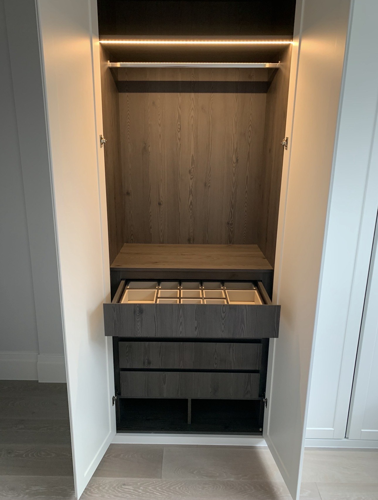 Close view of an open wardrobe with LED hanging rail and divided top drawer