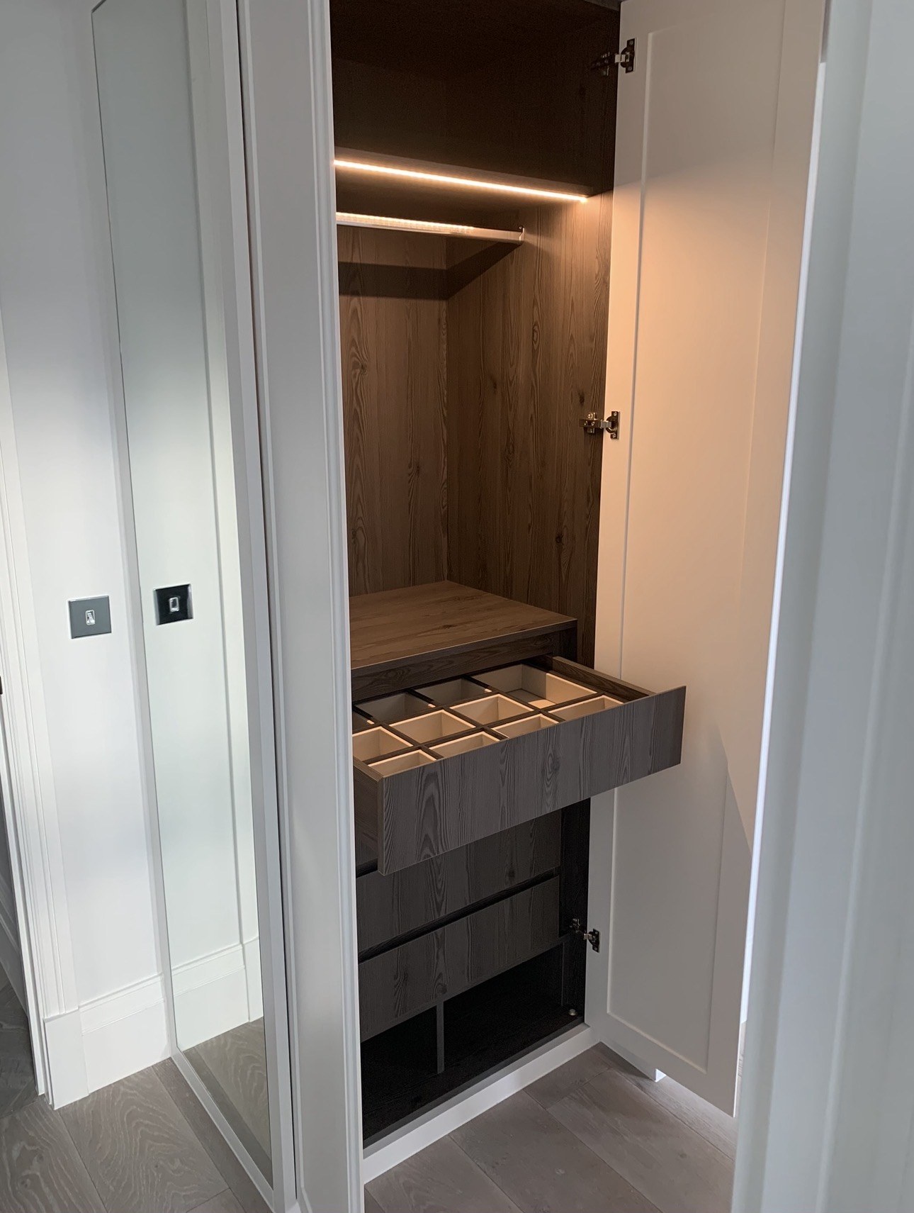 Open wardrobe with dark oak interior and illuminated hanging space