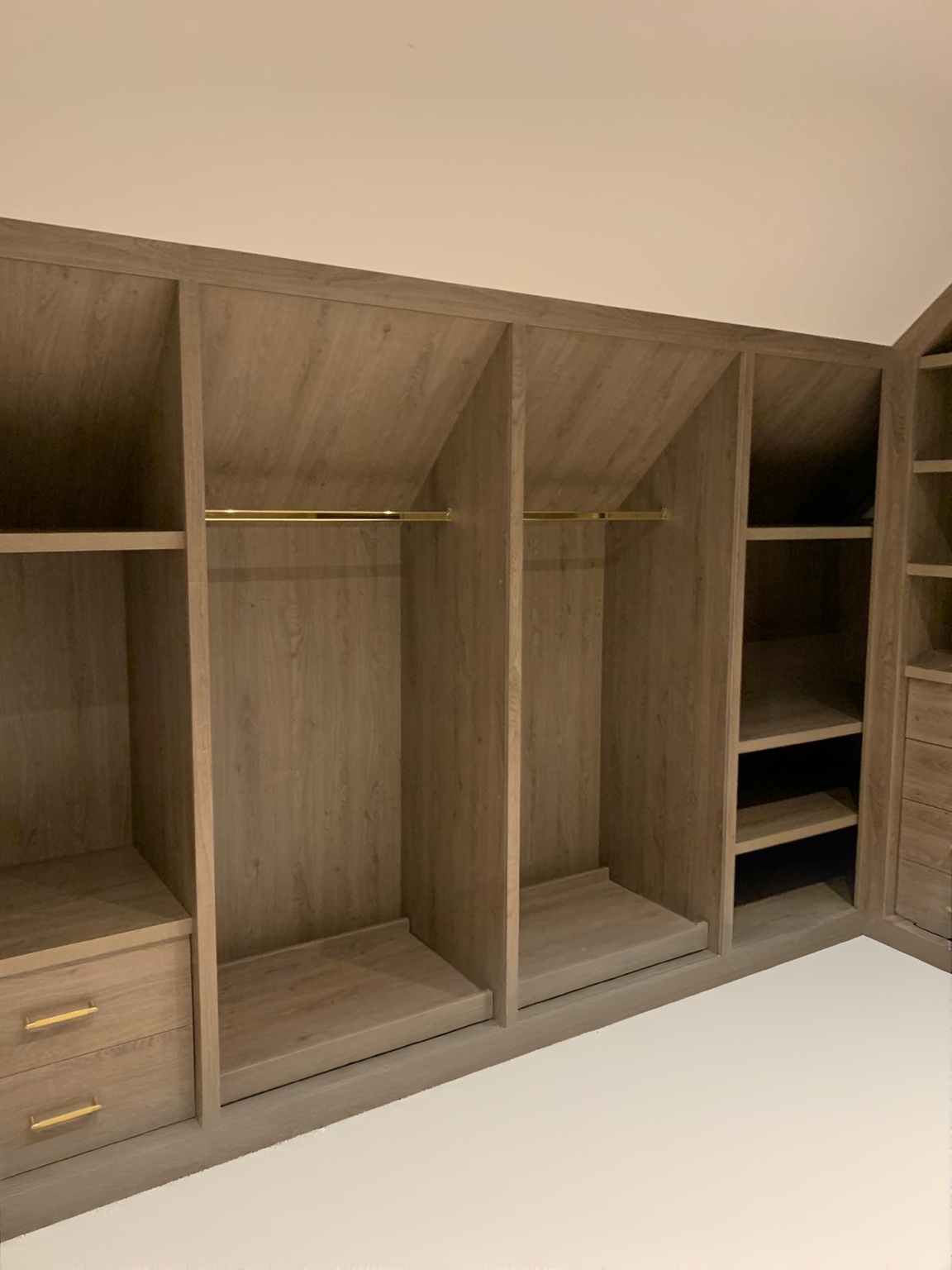 Close view of open hanging space and shelving with brass rails in the walk-in wardrobe